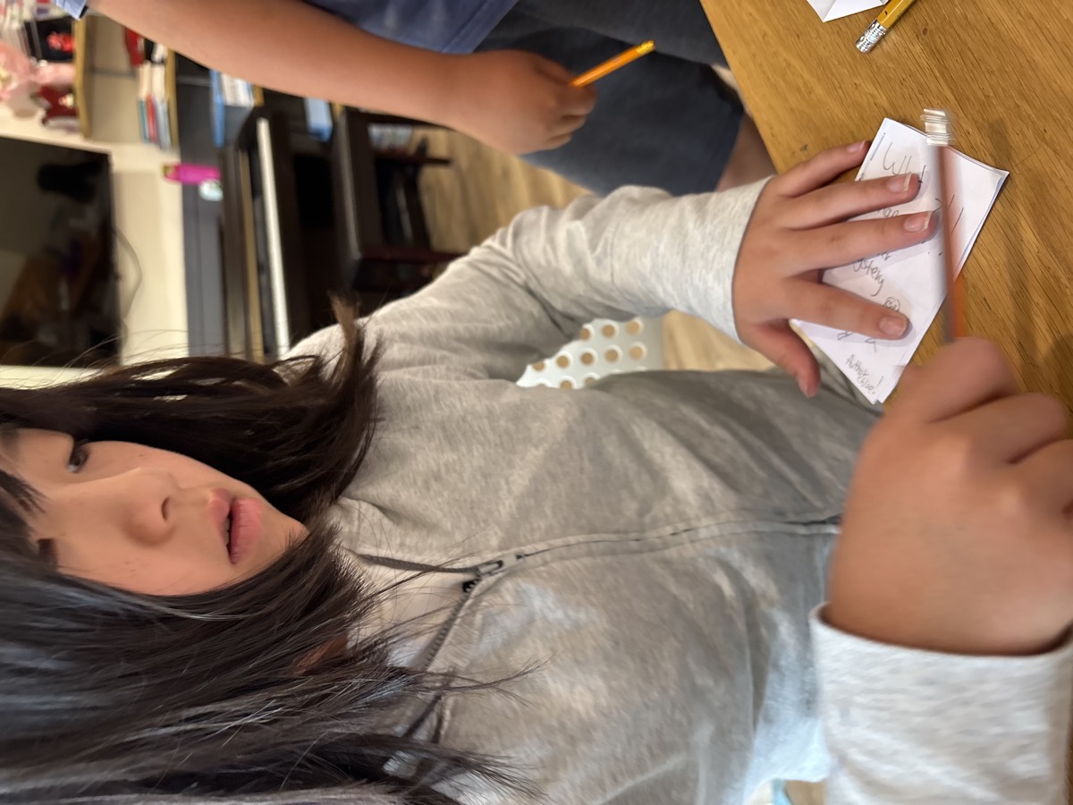A student carefully folding and pressing the pages of her mini booklet at the table