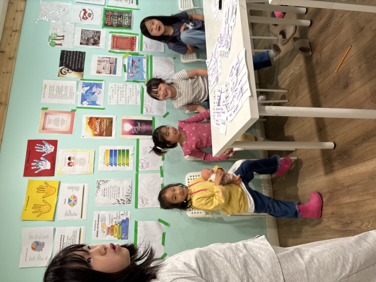 A group of students seated by the wall with their sentence strips spread out on the table