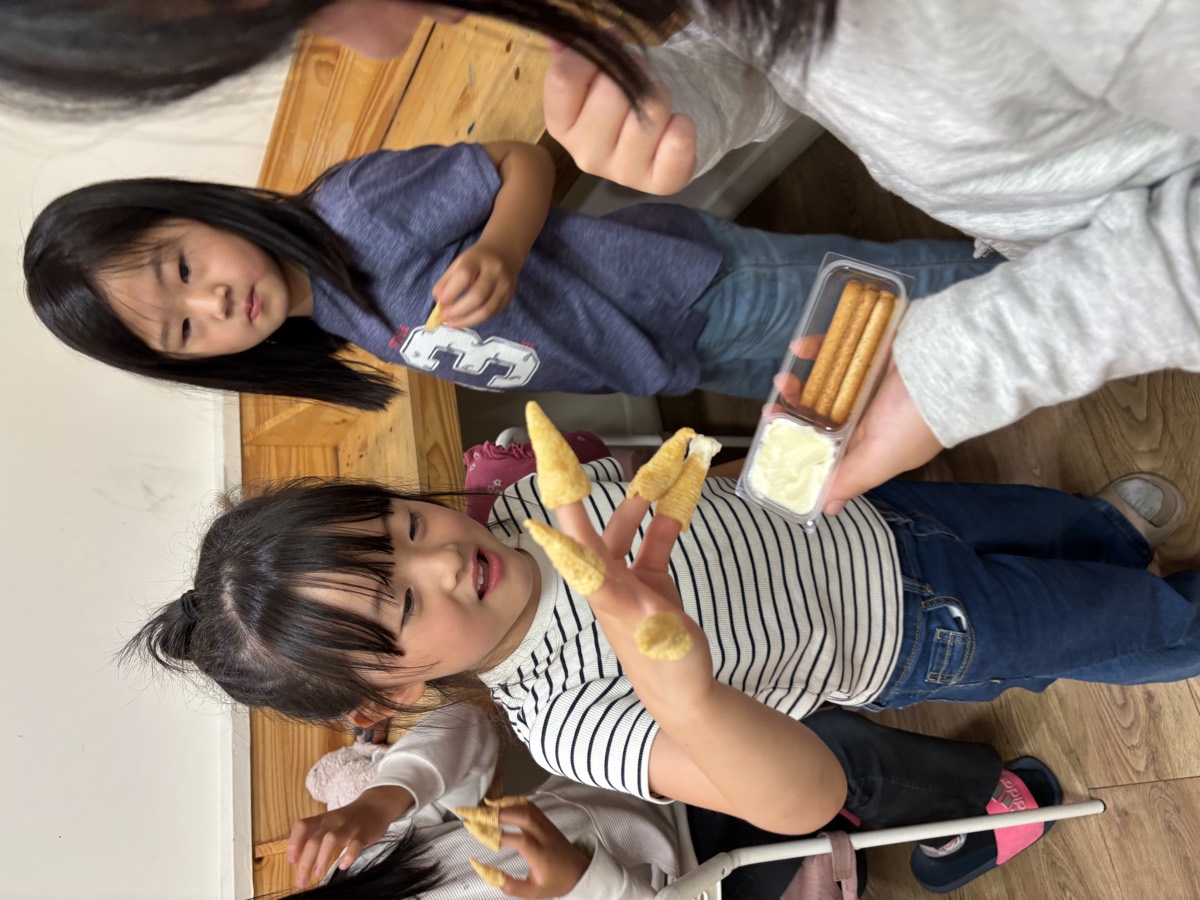 A smiling student wearing cone-shaped corn snacks on every fingertip like witch fingers