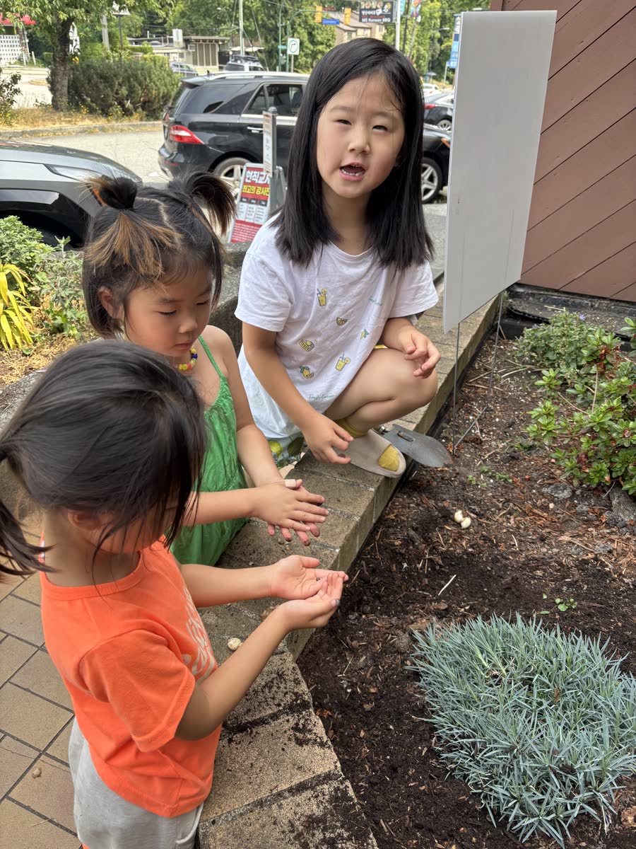 Children carefully tending soil around garden plants