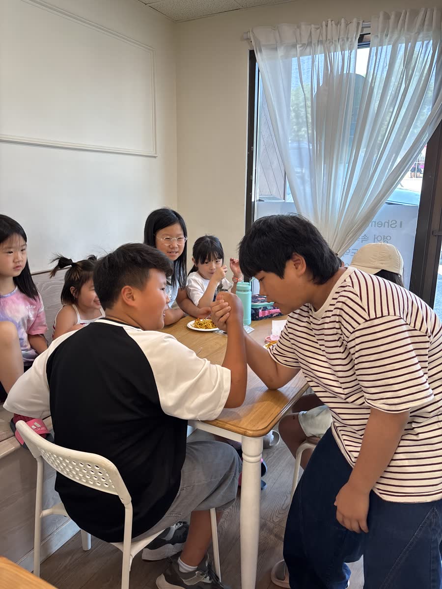 Two students smiling during a friendly arm-wrestling match