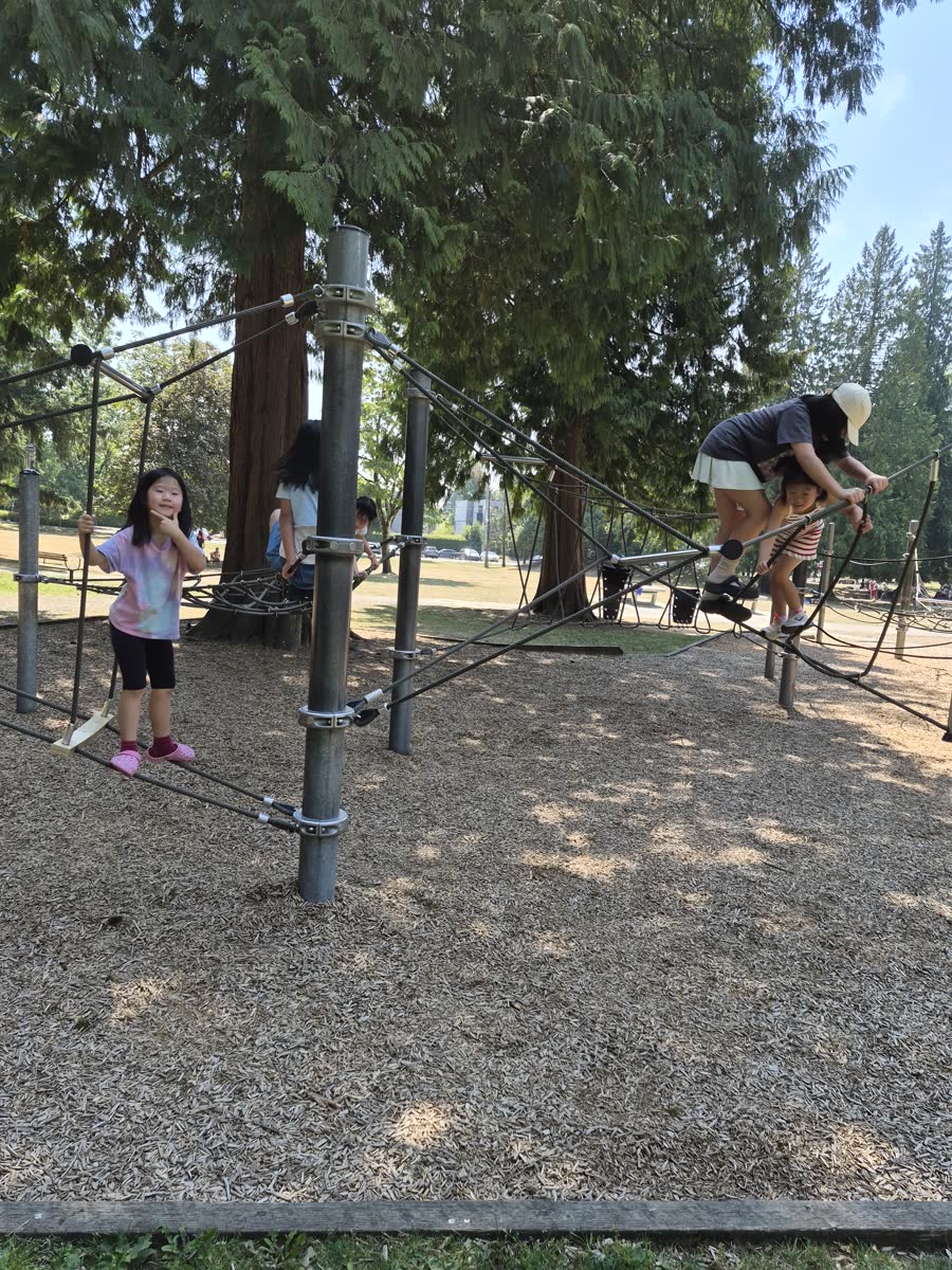 A student carefully climbing across a rope playground structure