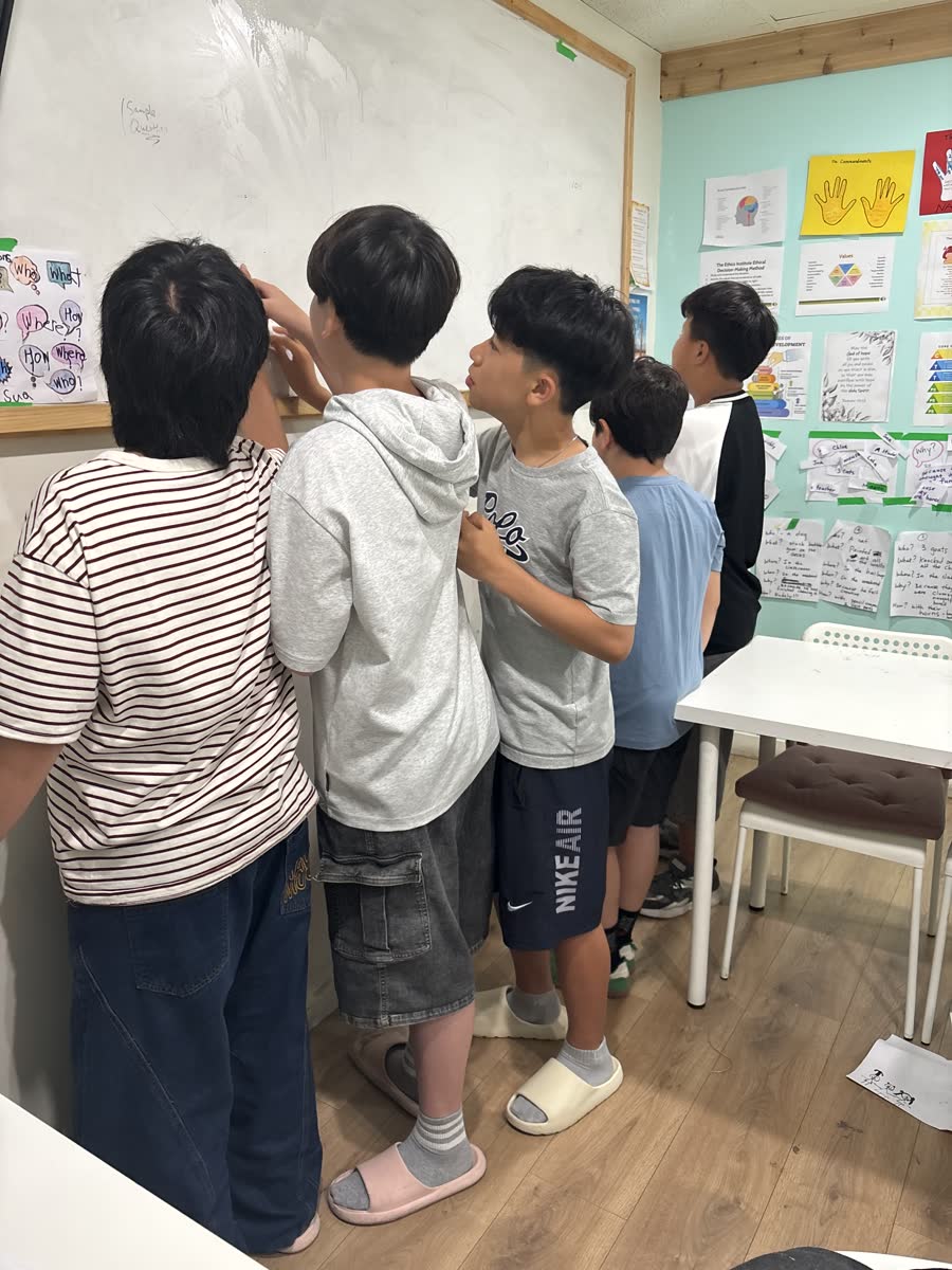 Students gathered closely around the whiteboard during the Jeopardy challenge