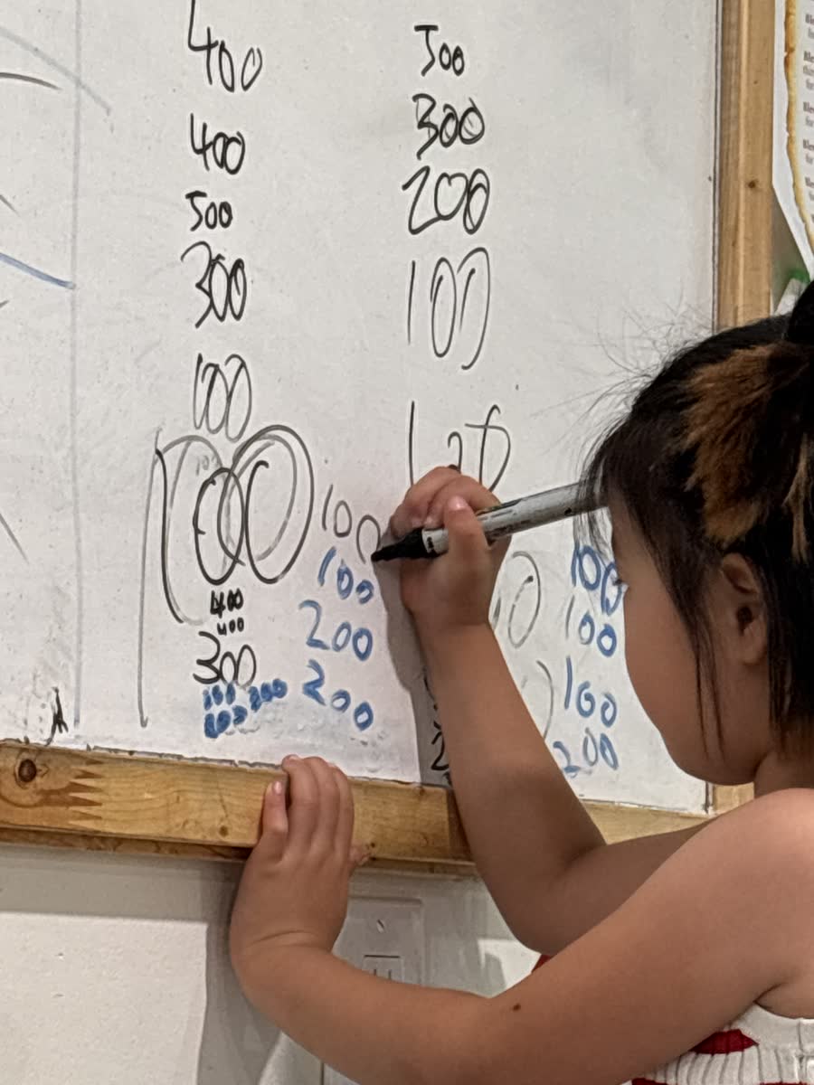 A student writing bonus points and totals on the whiteboard