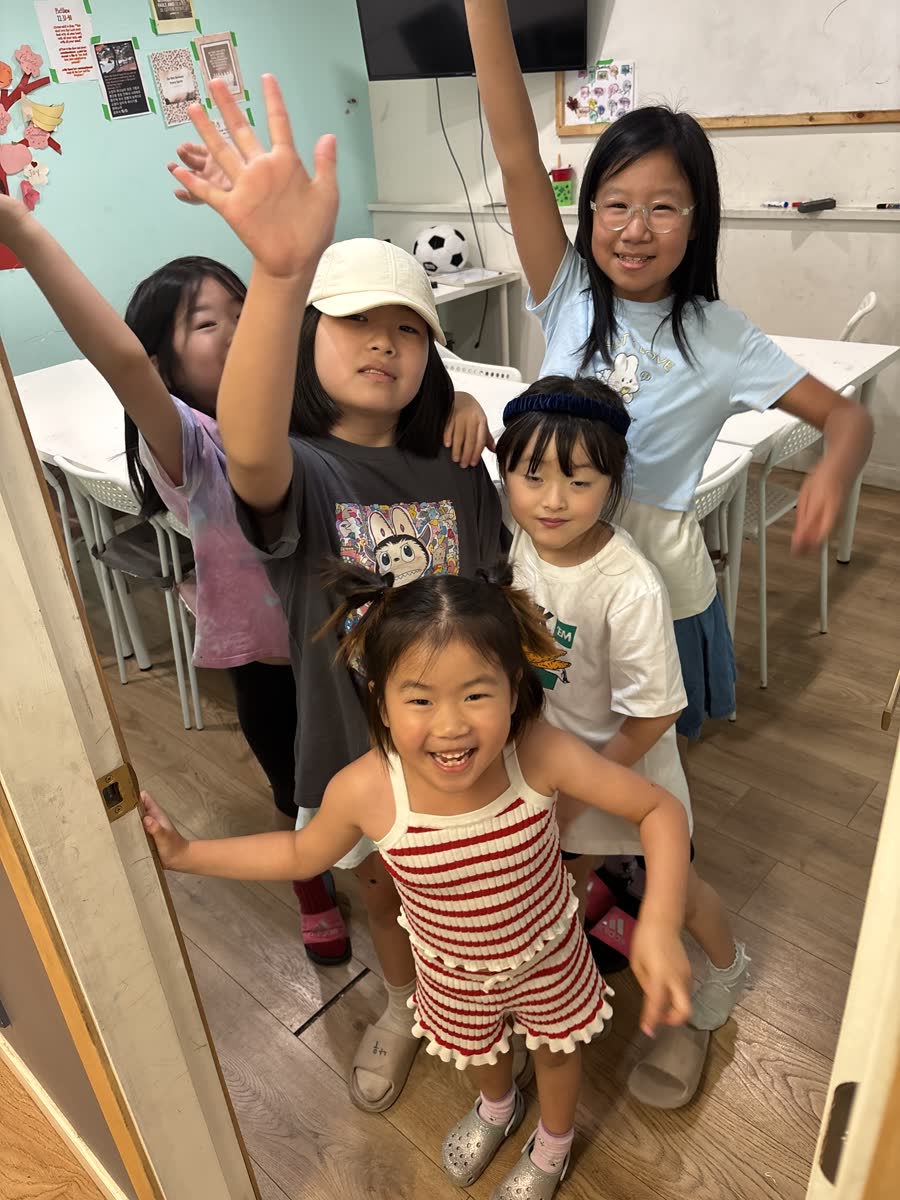 Five younger students cheering together in the classroom