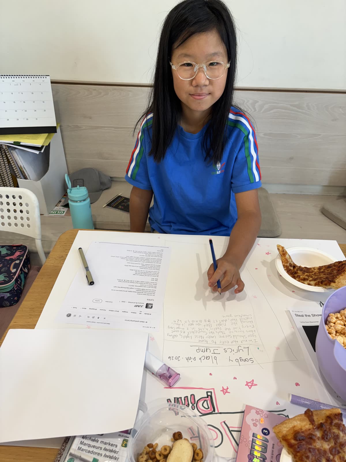 A student writing lyrics and planning a large song presentation poster