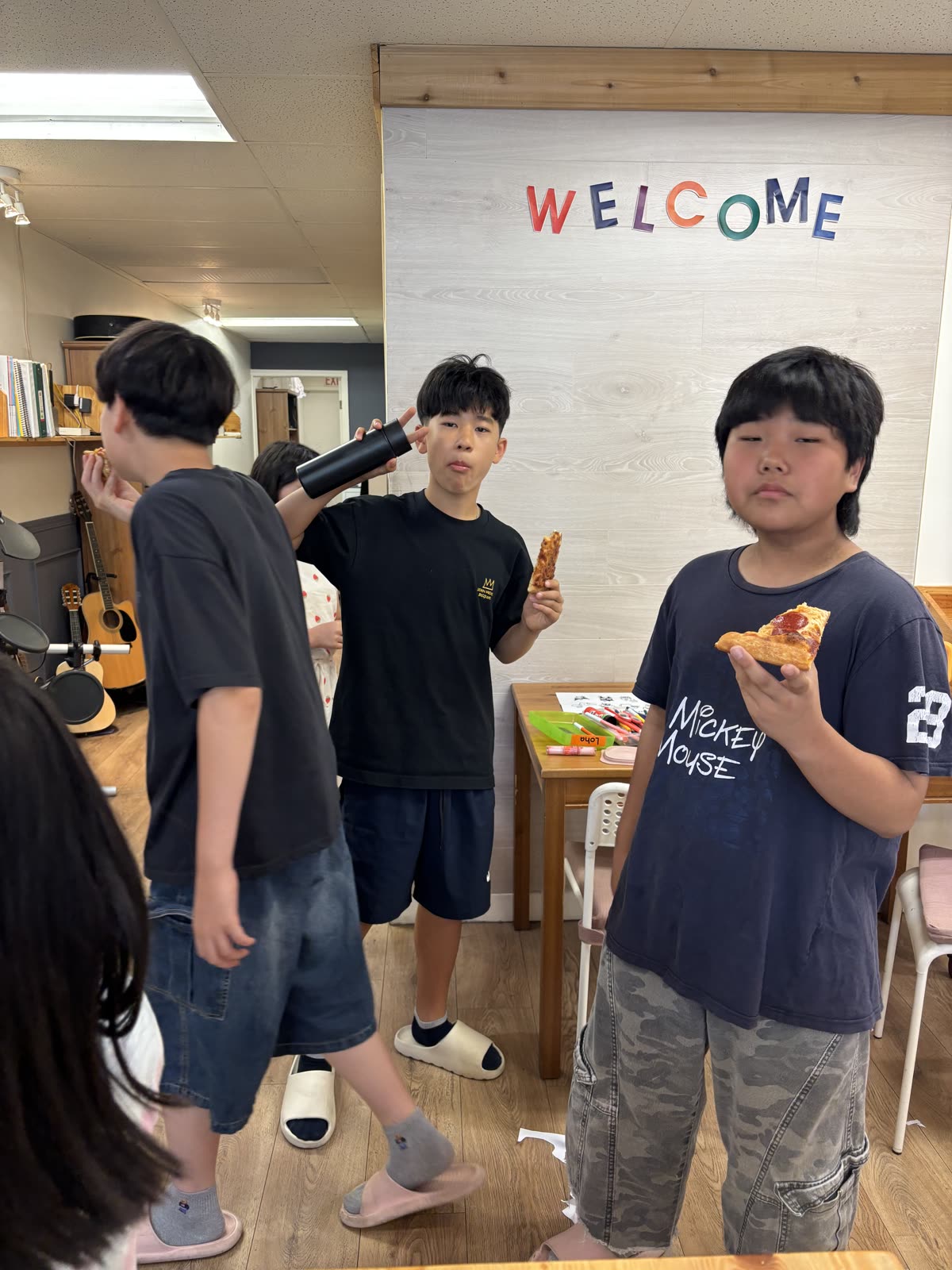 Older students enjoying pizza together beneath the welcome sign