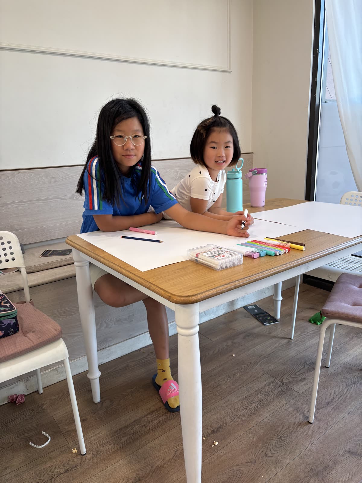 Two students seated together with markers and blank presentation boards