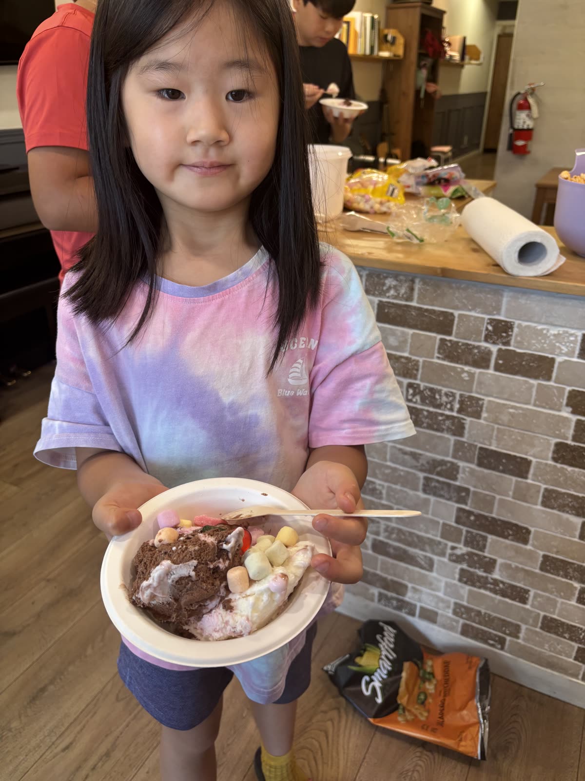 A student holding a colorful ice-cream sundae with fruit and cereal