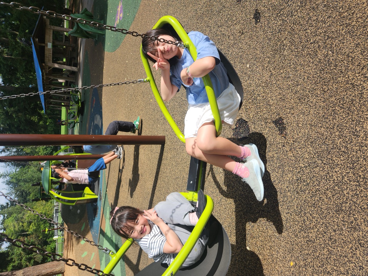 Two girls swinging and making peace signs at the playground