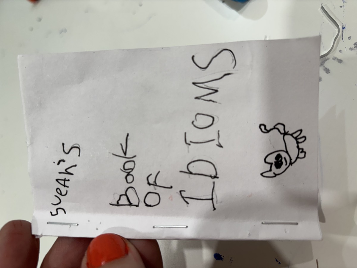 A handmade booklet cover reading Sueah's Book of Idioms with a small drawing of an animal