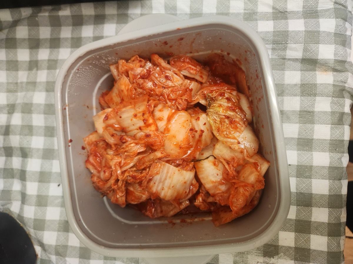 A container of freshly made kimchi on a checked cloth