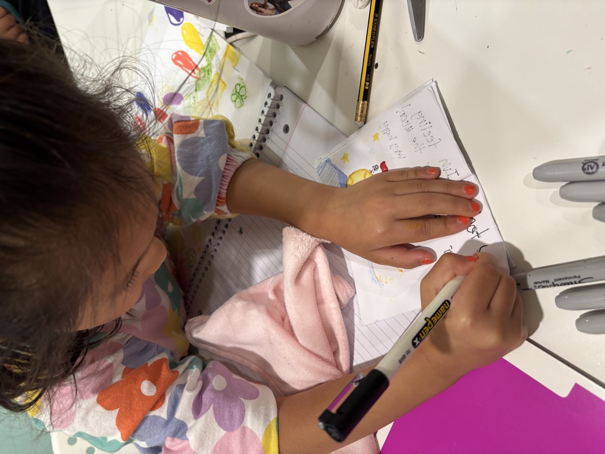 A young student colouring in the illustrations on her idiom booklet page