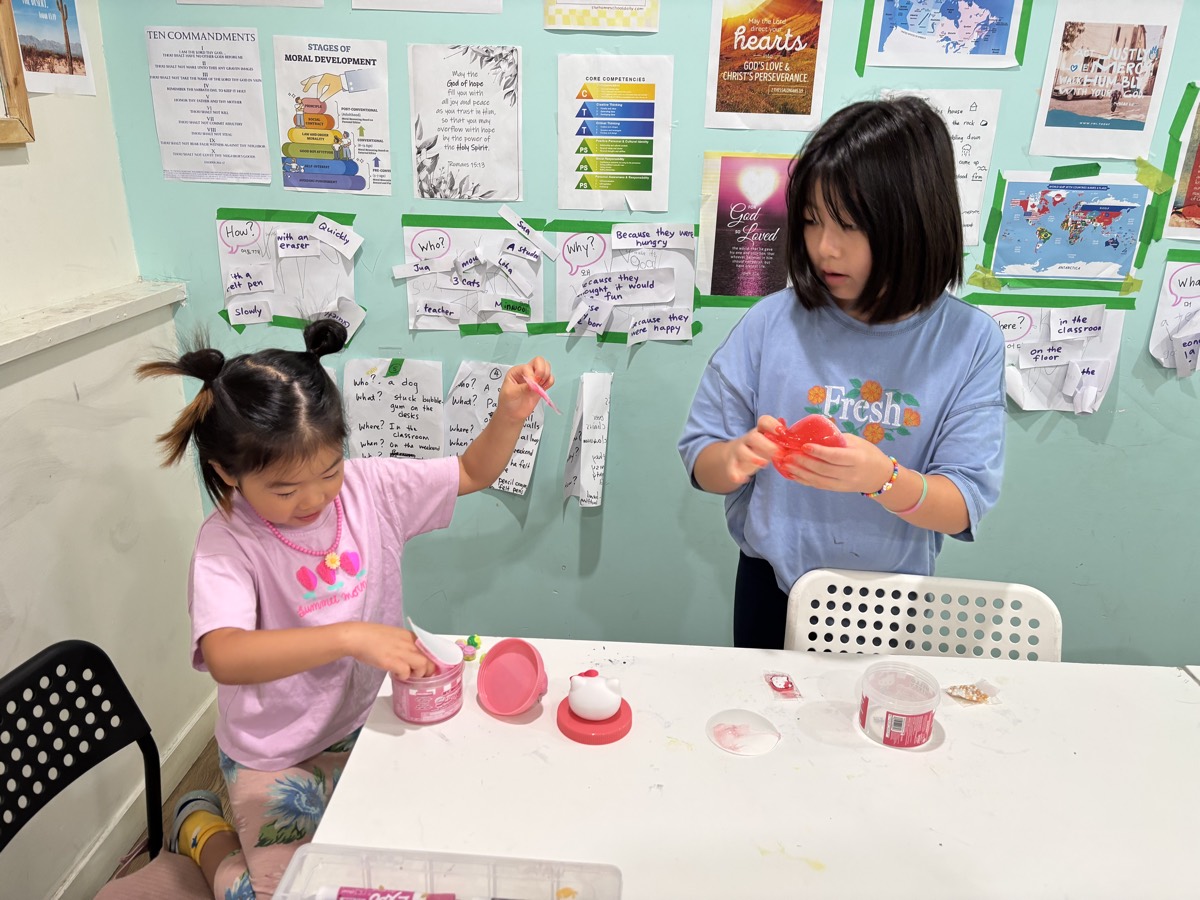 Two students standing at the table working with modelling clay and small cups