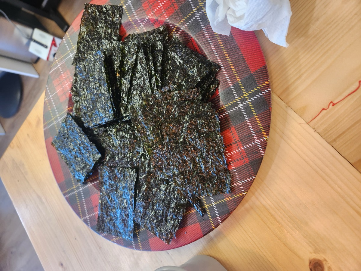 Sheets of roasted seaweed laid out on a round plate on the wooden table