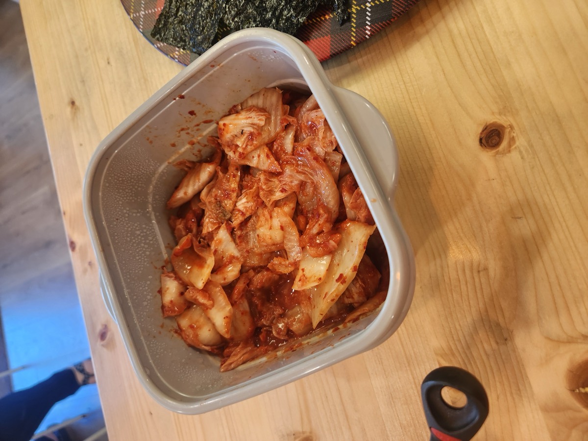 A container of kimchi on the wooden lunch table