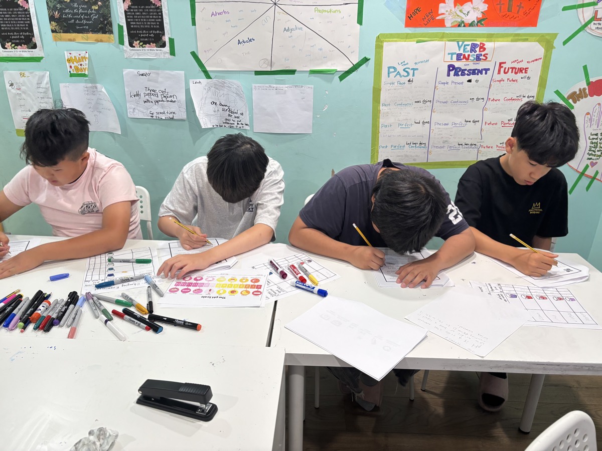 Four students working side by side along the table, each filling in their own experiment sheet