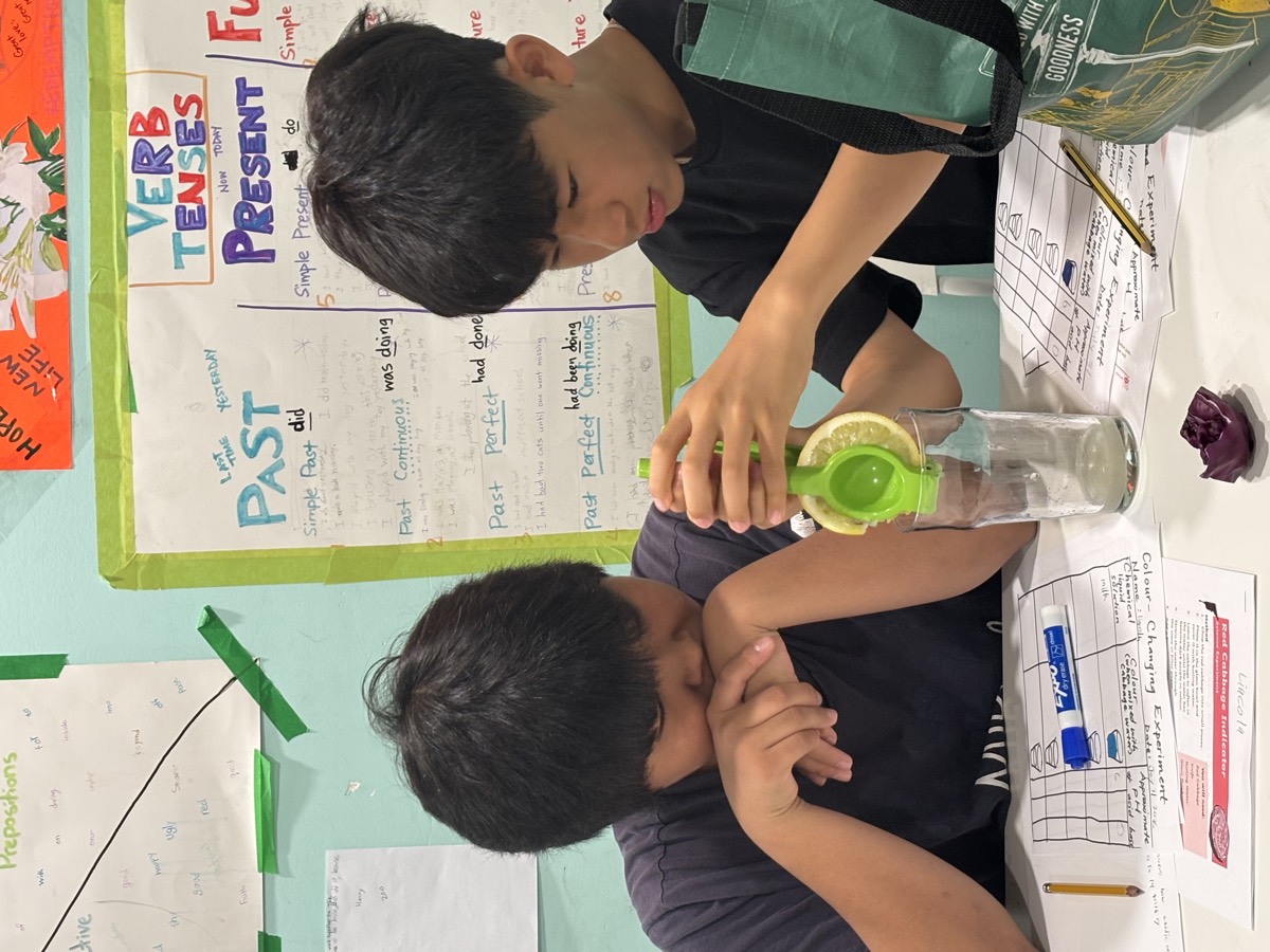 Two older students carefully handling a bottle over a jar during the experiment