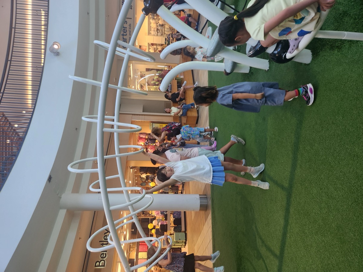 Children running and reaching up to the white loops of the indoor play structure