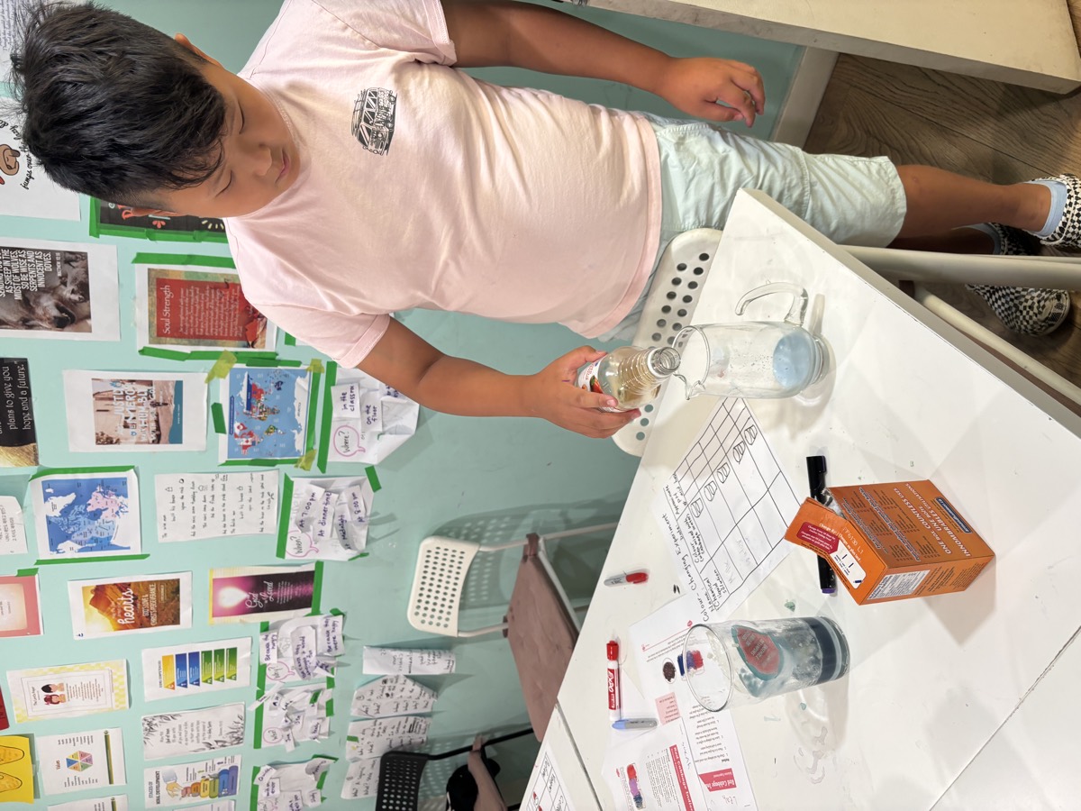 A student standing at the table adding liquid to a jar during the experiment