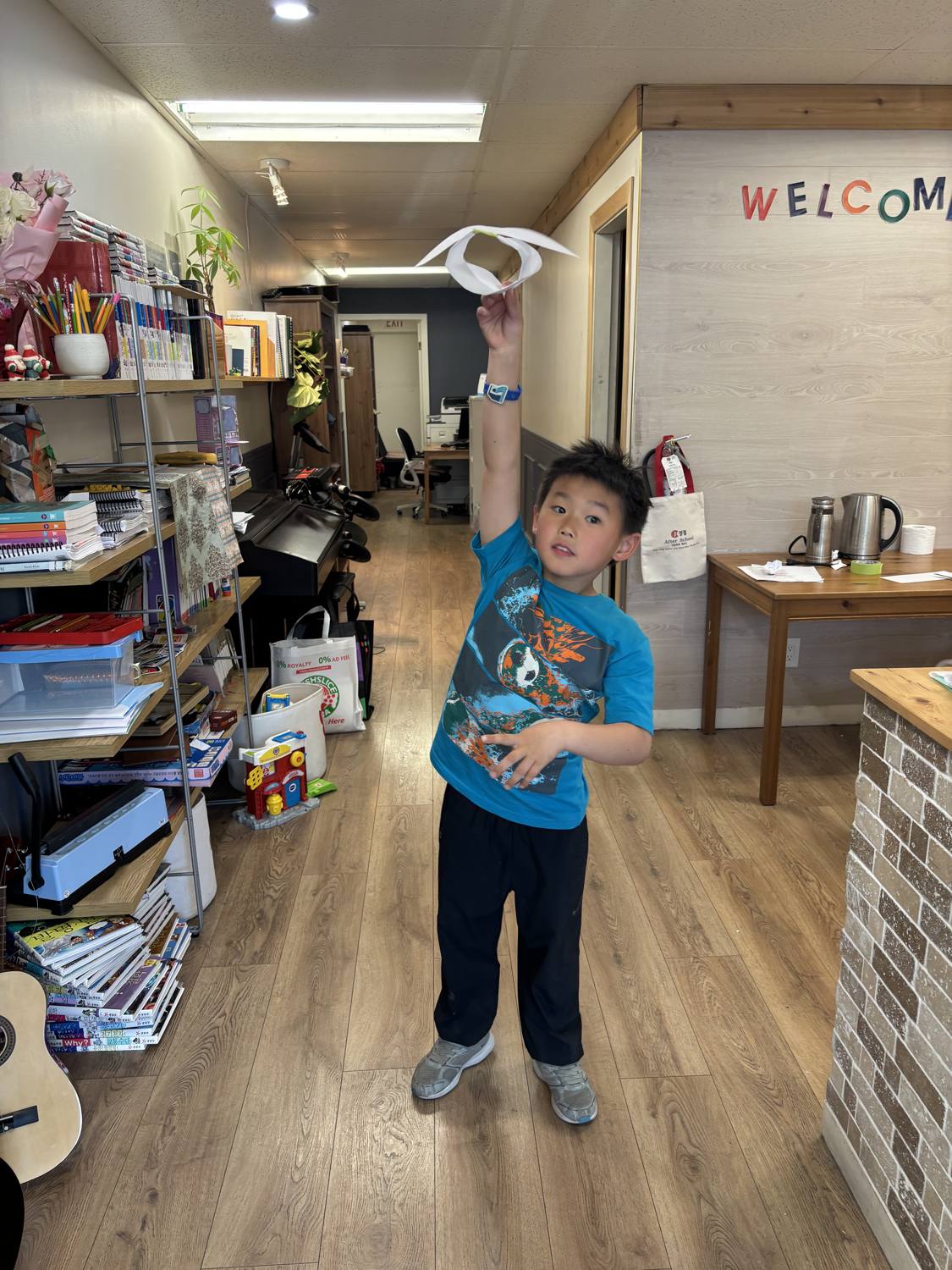 A student launching his paper glider in the WELCOME hallway